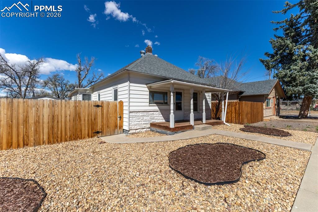 Image 1 of 40: Rear view of property with covered porch, a chimney, stone siding, a shingl
