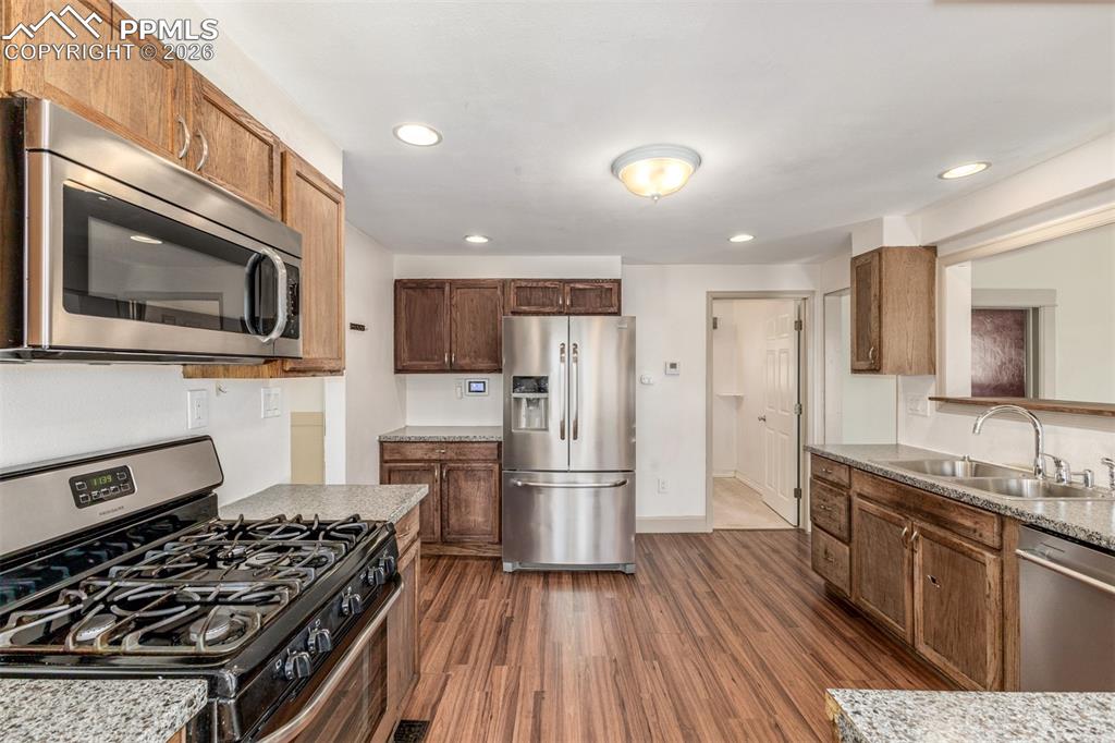 Image 13 of 40: Kitchen with stainless steel appliances, dark wood-style flooring, recessed