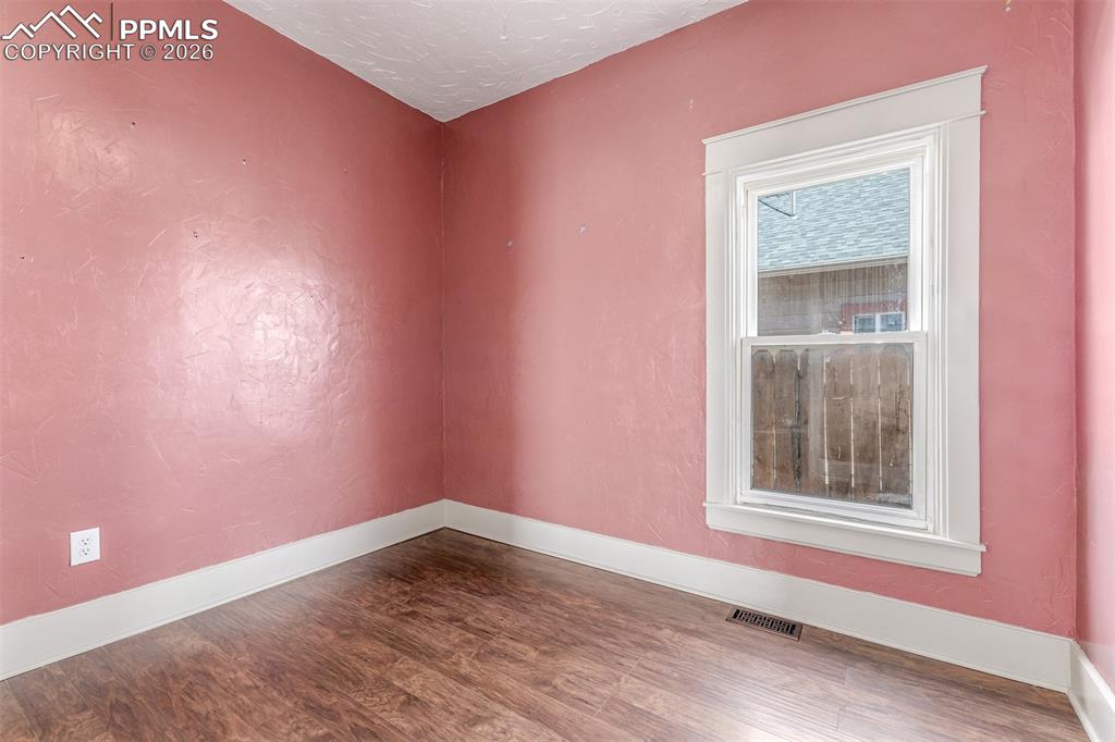 Image 15 of 40: Empty room with wood finished floors and a textured ceiling