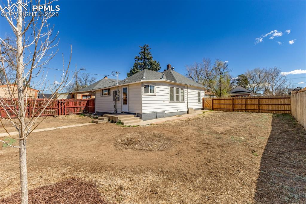 Image 28 of 40: Rear view of house with a fenced backyard