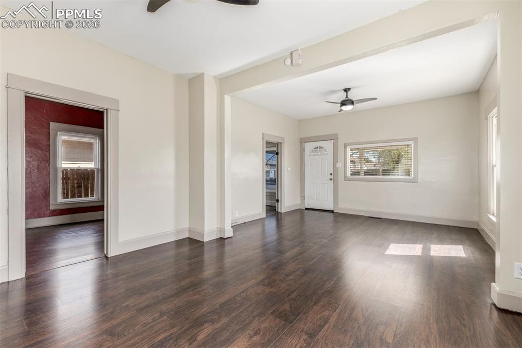 Image 8 of 40: Unfurnished living room with a ceiling fan and dark wood-style floors