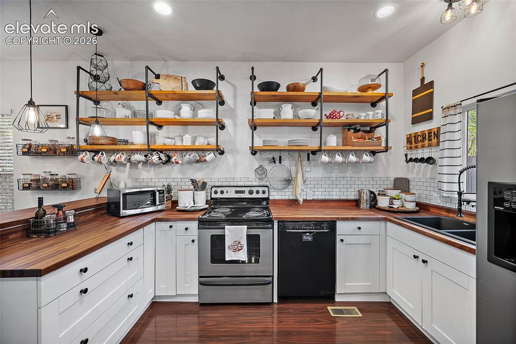 Image 3 of 35: Updated kitchen with stainless steel appliances and butcher block countert