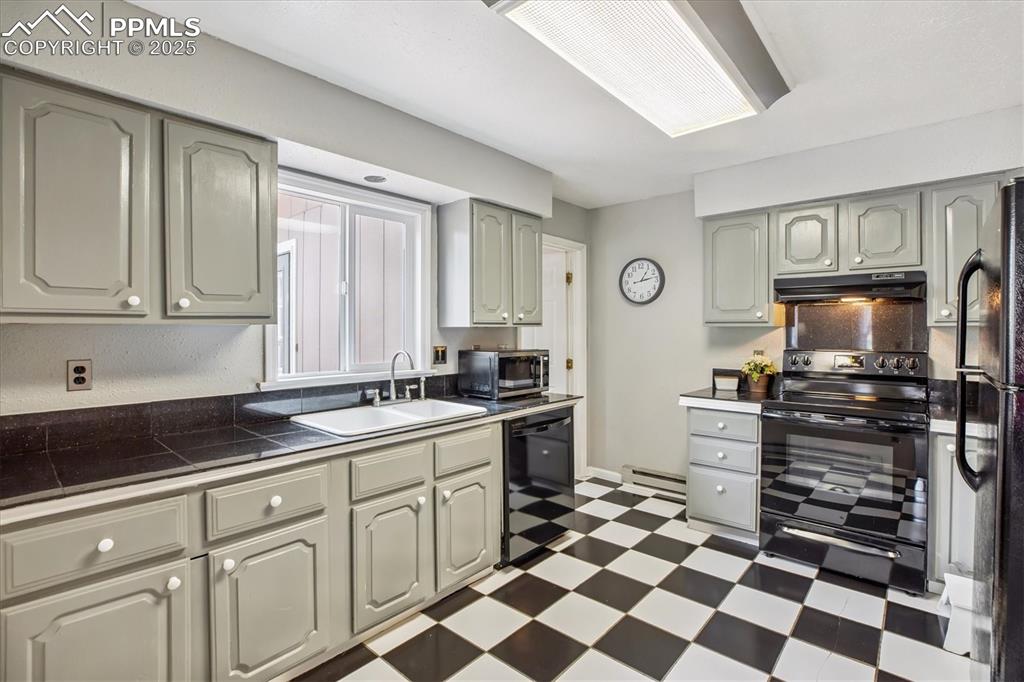 Image 12 of 29: Kitchen area with updated painted cabinets and sleek black appliances