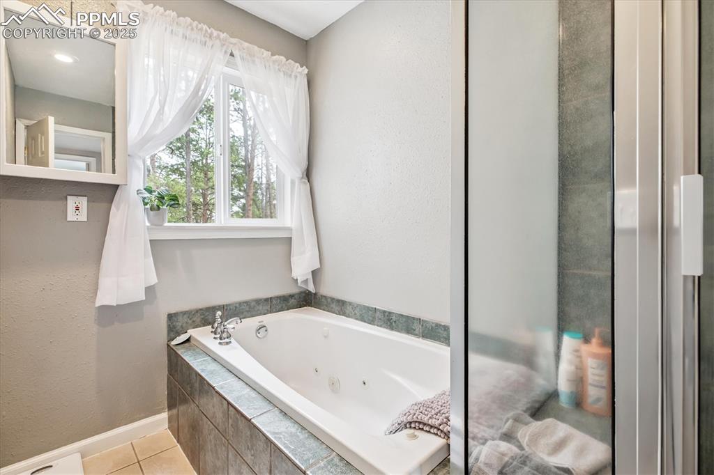 Image 16 of 29: Full bathroom with a tub with jets and tile patterned floors