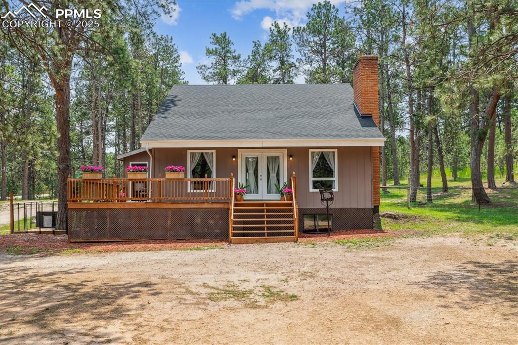 Image 2 of 29: View of front of home featuring french doors and wraparound deck
