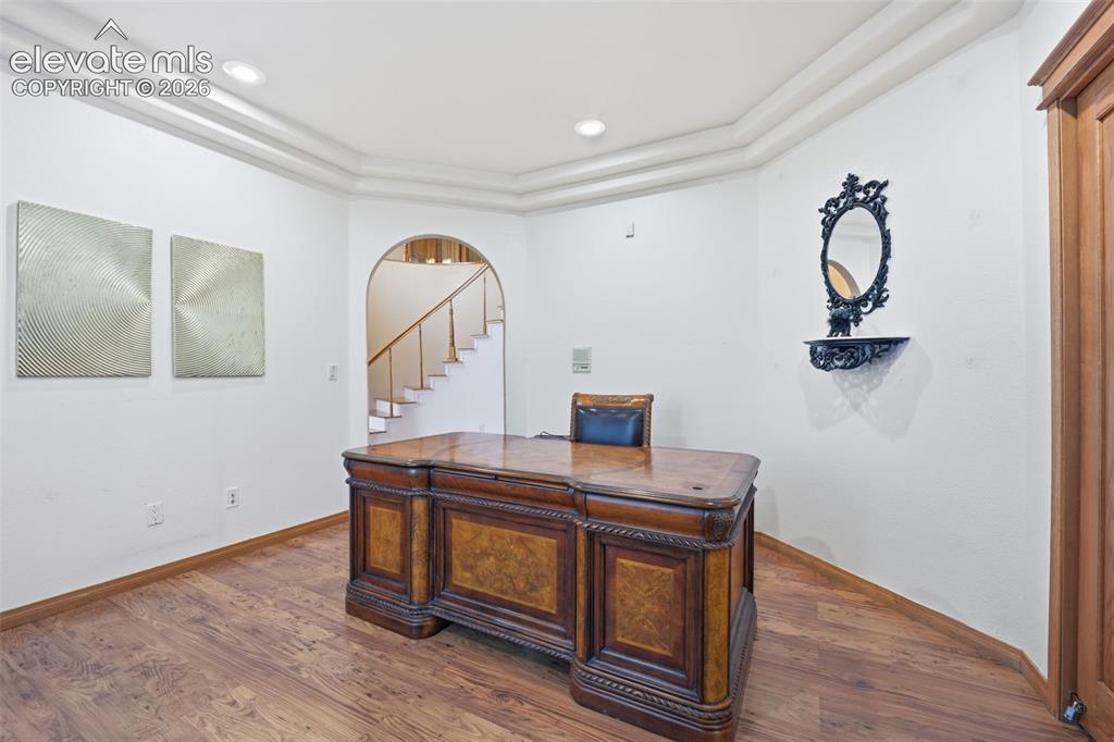 Image 12 of 49: Wood-finish flooring, recessed lighting, crown molding, and an arched entry