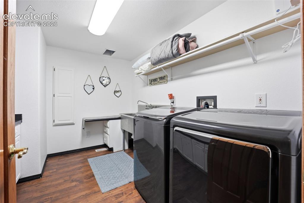 Image 13 of 49: Laundry area featuring wood-finish flooring, a utility sink, and built-in s