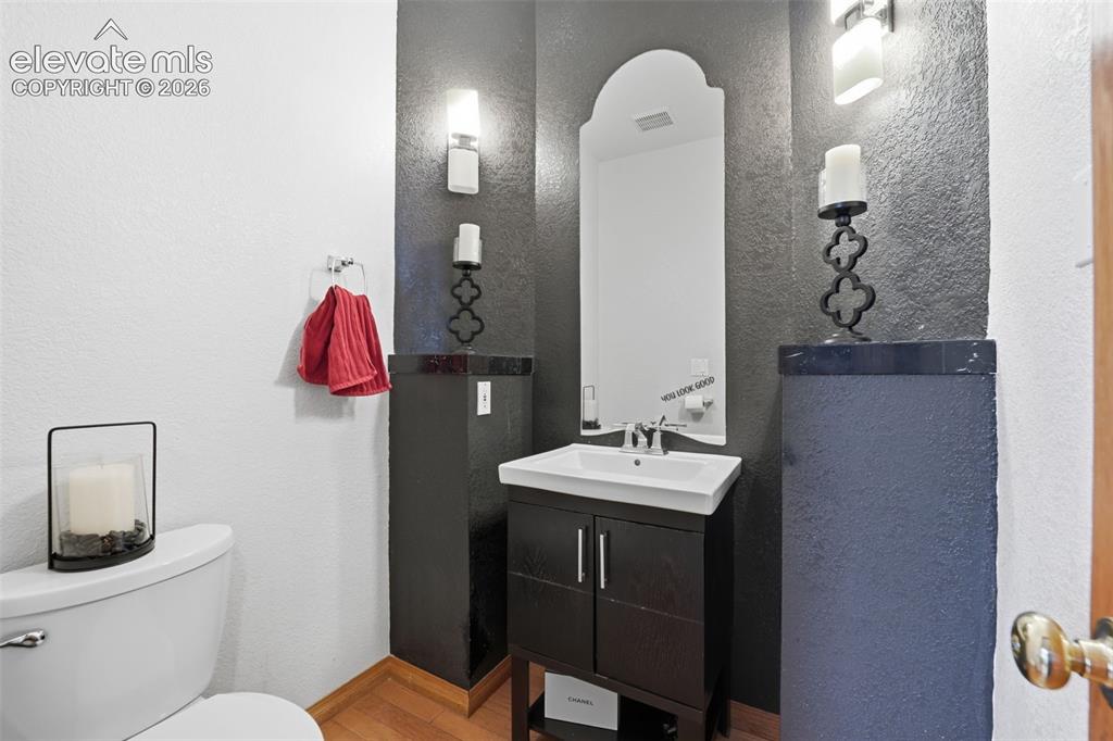 Image 15 of 49: Pedestal sink with chrome faucet, arched mirror, wall-mounted sconces, and 