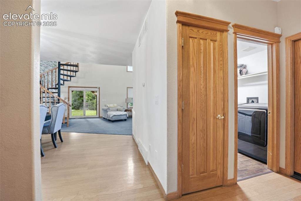 Image 16 of 49: Light wood-finish flooring with a spiral staircase featuring wood treads