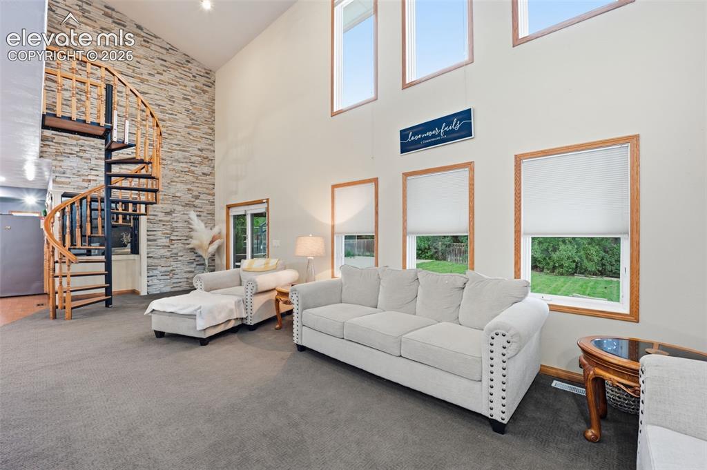 Image 18 of 49: Soaring ceiling with high windows, natural wood-frame windows, stone accent