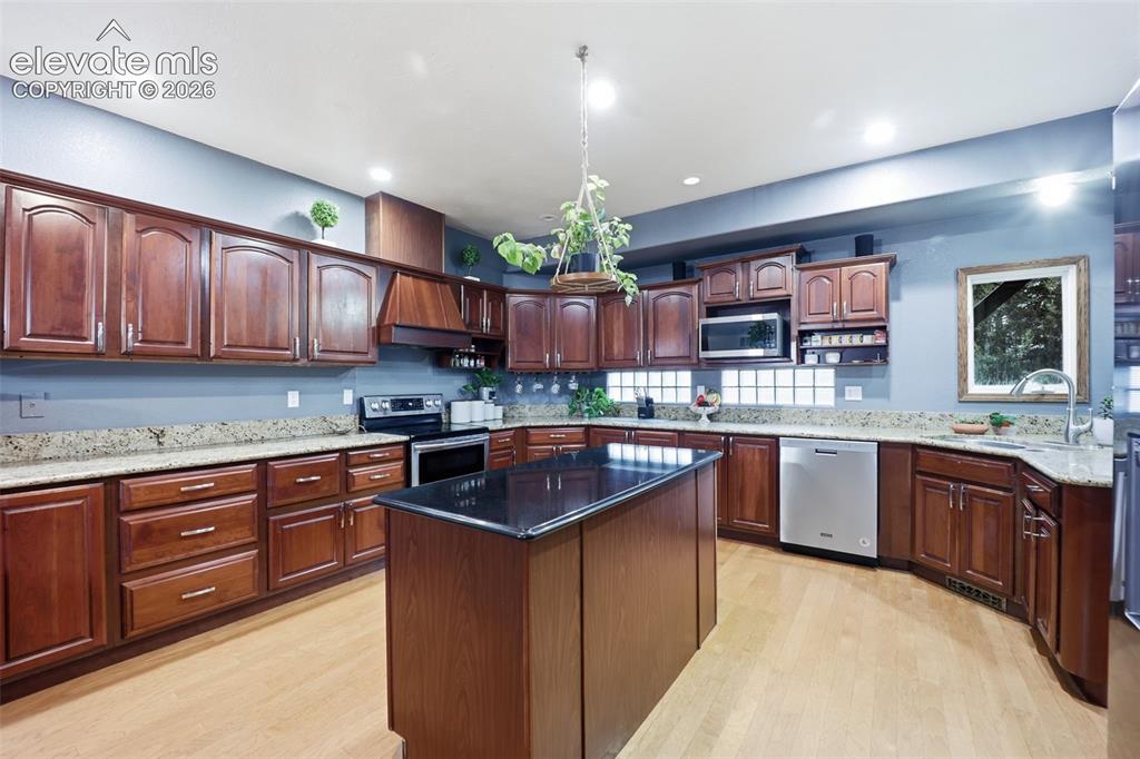 Image 2 of 49: Kitchen featuring wood-finish flooring, abundant wood cabinetry, granite-fi