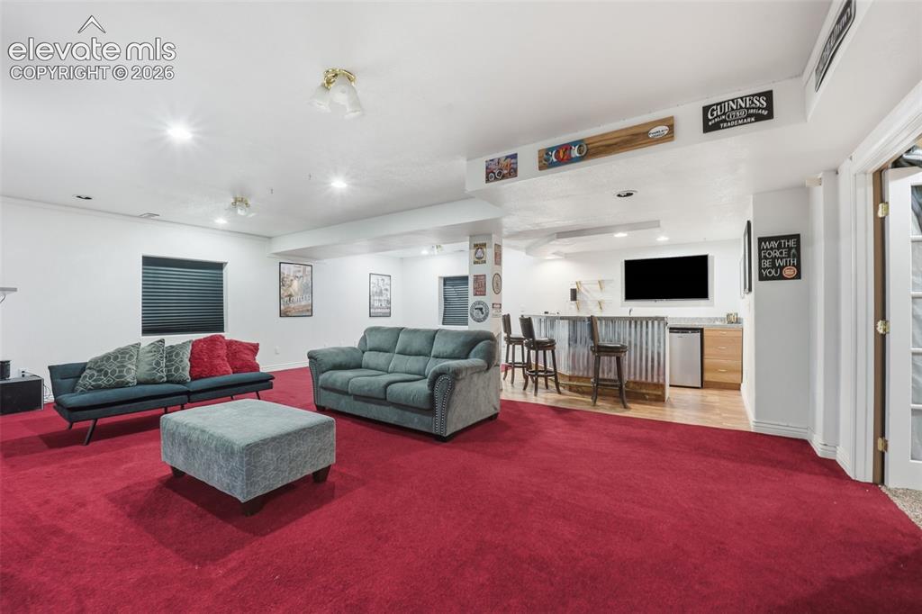 Image 23 of 49: Spacious finished basement featuring recessed lighting, a built-in bar with