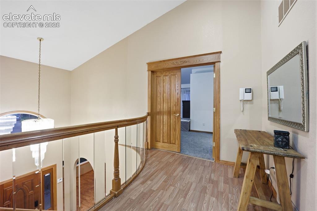 Image 25 of 49: Wood-finish flooring, wood-paneled door, and a curved staircase with wood r