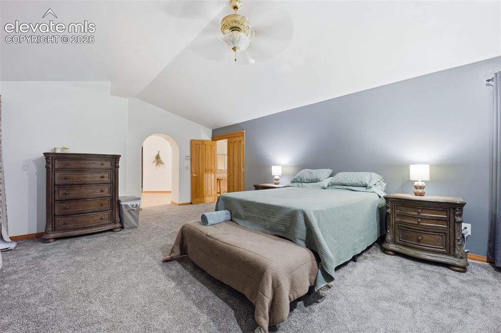Image 27 of 49: Vaulted ceiling with a ceiling fan, arched doorway, and wood-finish doors