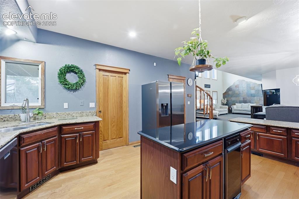 Image 3 of 49: Kitchen featuring wood-finish flooring, wood cabinetry, granite countertops