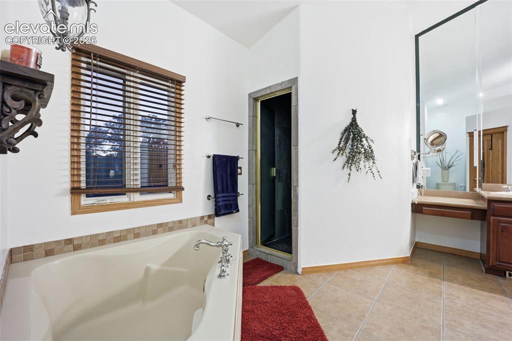 Image 31 of 49: Built-in soaking tub with chrome fixtures, tiled surround, and wood-finish
