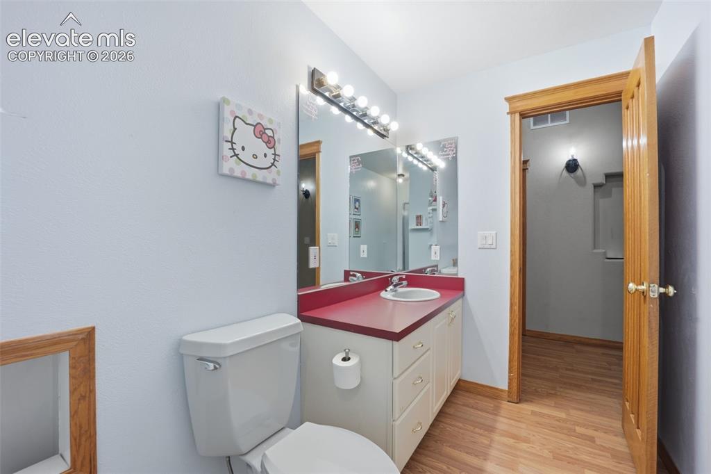 Image 33 of 49: Bathroom featuring a single vanity with a red countertop, integrated sink,