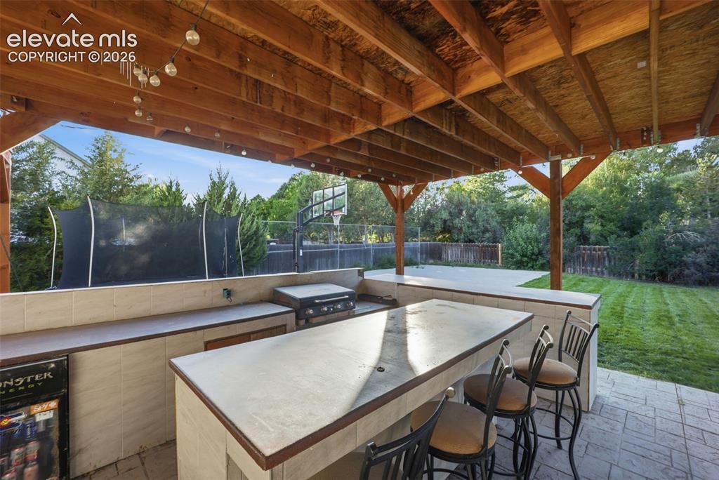 Image 37 of 49: Expansive covered patio featuring a built-in outdoor kitchen with a grill,