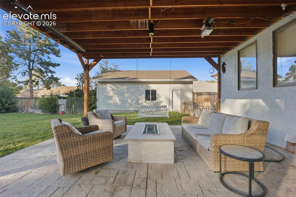 Image 38 of 49: Covered patio with stamped concrete flooring, exposed wood beam ceiling, an
