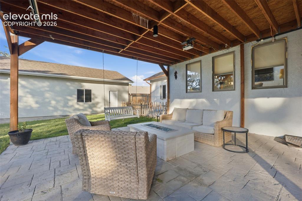 Image 39 of 49: Covered patio with exposed wood beam ceiling, stamped concrete flooring, an