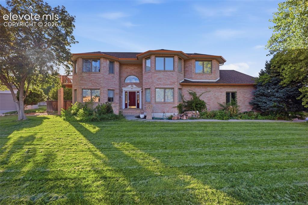 Image 40 of 49: Brick exterior with multiple bay windows, an arched entry, and a large fron