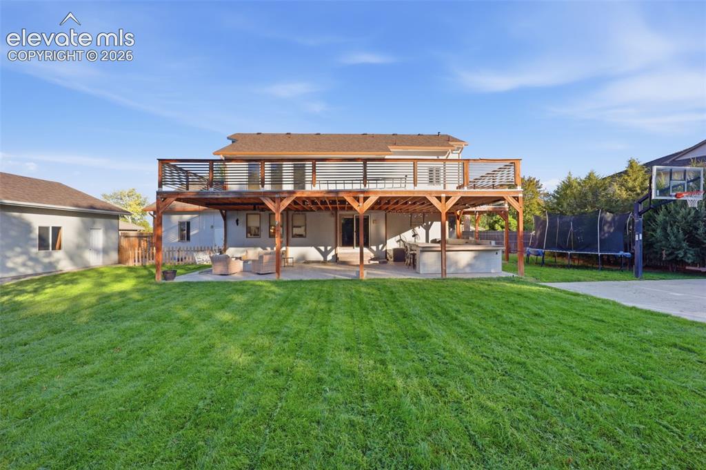 Image 41 of 49: Expansive backyard featuring a manicured lawn, multi-level wooden deck with