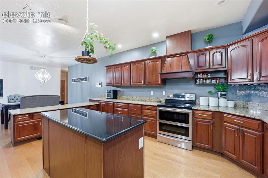 Image 6 of 49: Kitchen featuring wood cabinetry, granite countertops, a central island wit