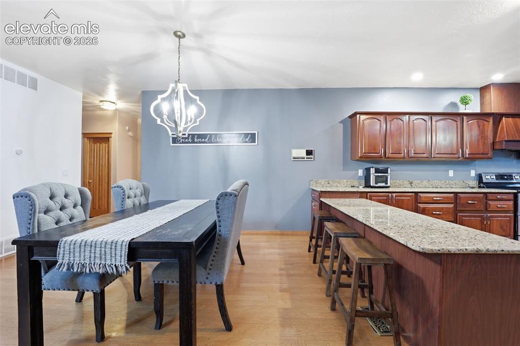 Image 7 of 49: Wood-finish flooring throughout, with a decorative chandelier in the dining