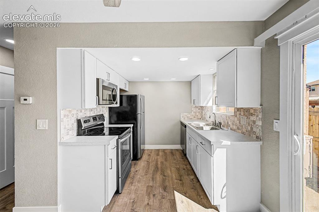 Image 11 of 31: Galley kitchen featuring white cabinetry, light-toned countertops, stainles