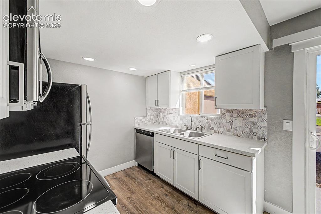 Image 13 of 31: Kitchen featuring white cabinetry, wood-finish flooring, stainless steel di