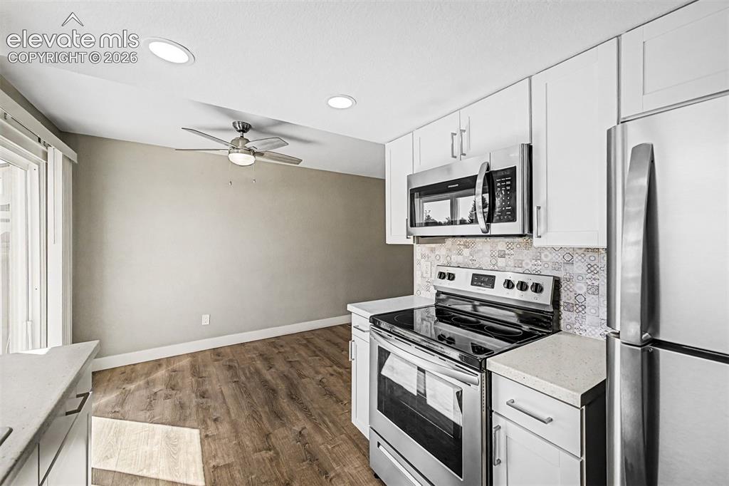 Image 14 of 31: Kitchen featuring white cabinetry, stainless steel appliances, patterned ba