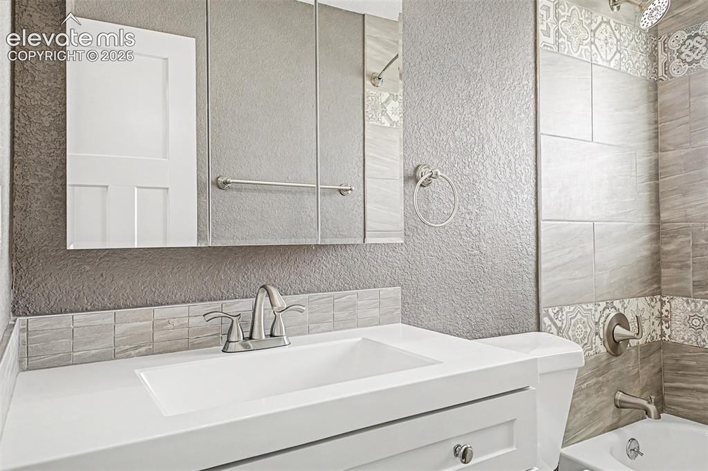 Image 22 of 31: White vanity with brushed nickel hardware, integrated sink, and brushed nic