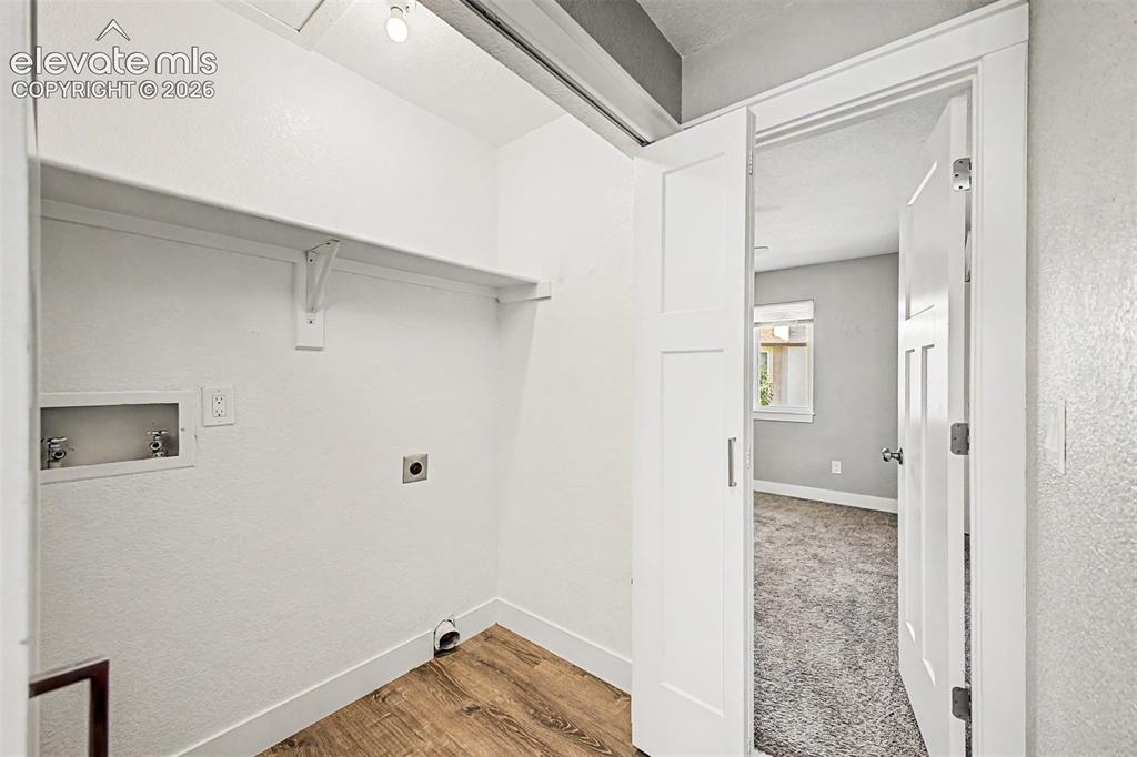Image 23 of 31: Dedicated laundry area featuring a built-in shelf, wood-finish flooring, an