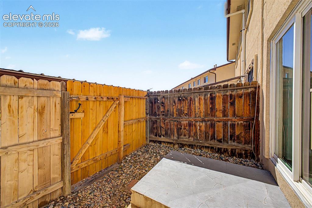 Image 25 of 31: Private outdoor space with wooden fencing, a secured gate, and a concrete p