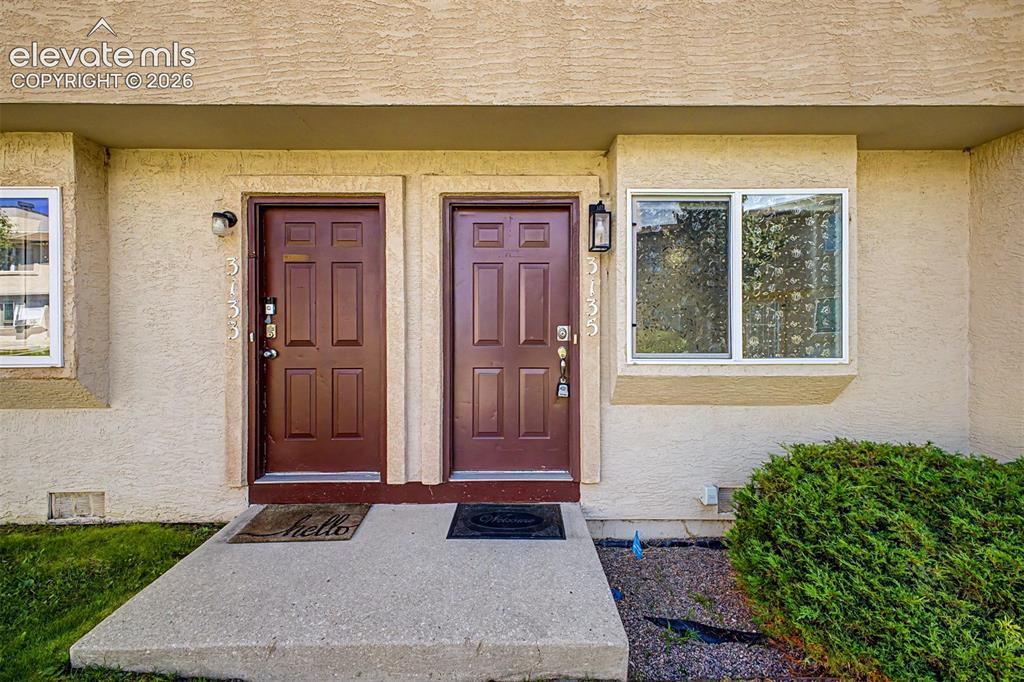 Image 31 of 31: Stucco exterior featuring two paneled entry doors with sconce lighting