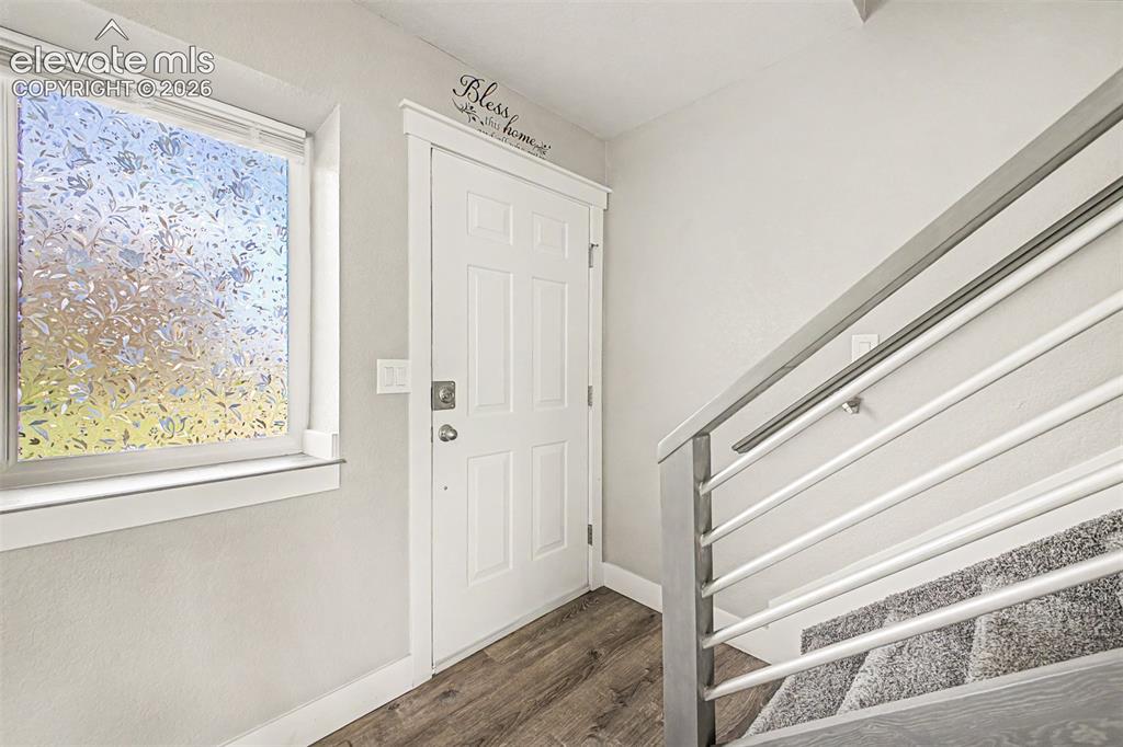 Image 4 of 31: Wood-finish flooring, white paneled door, and textured window