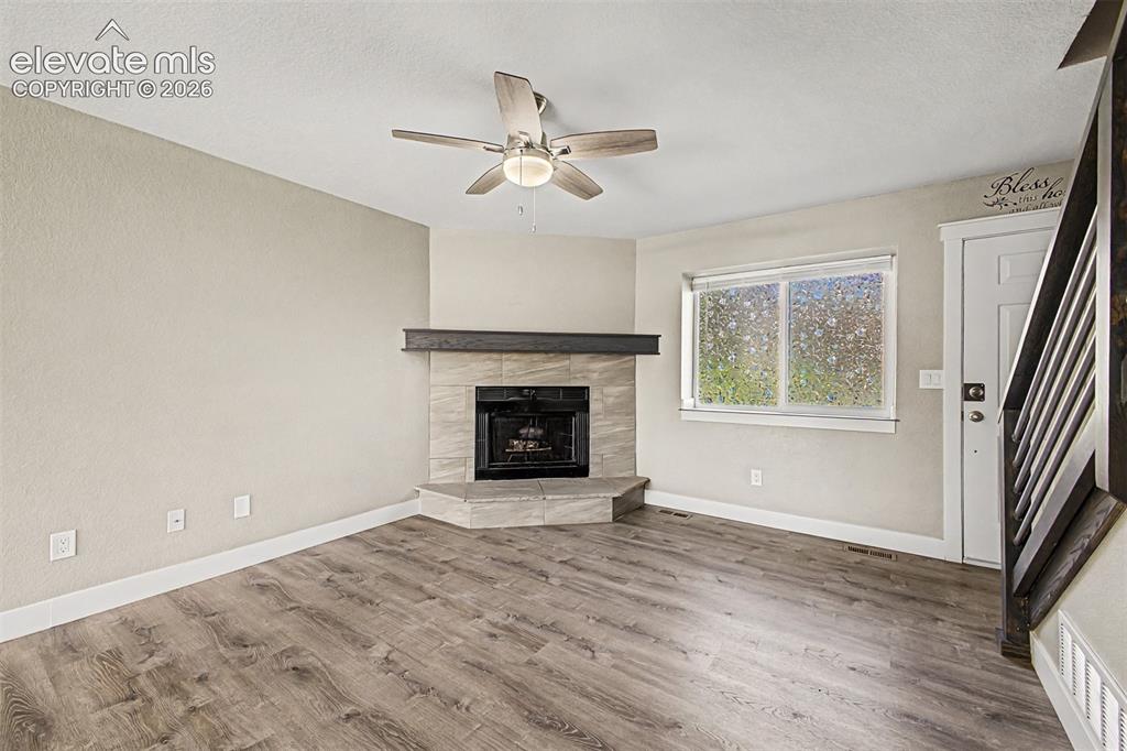 Image 6 of 31: Wood-finish flooring, corner fireplace with tile surround and wood mantel, 