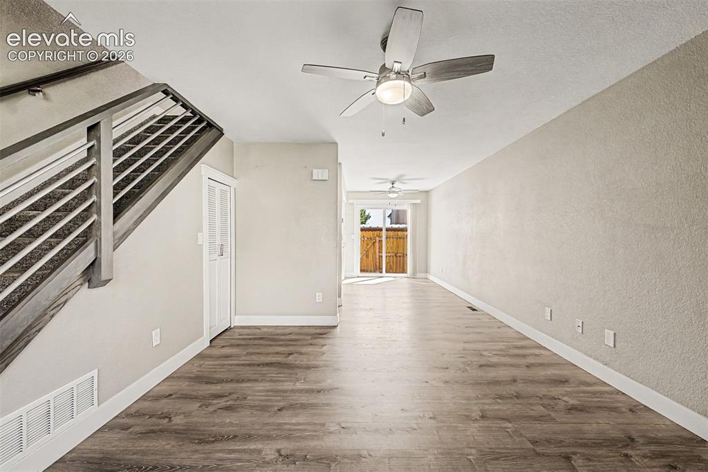 Image 8 of 31: Wood-finish flooring, staircase with metal balusters, ceiling fans, white t