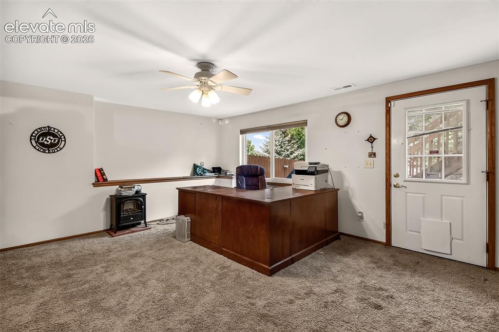Image 26 of 41: Bright Basement Area Used for a Home Office. Note Electric Free-Standing F