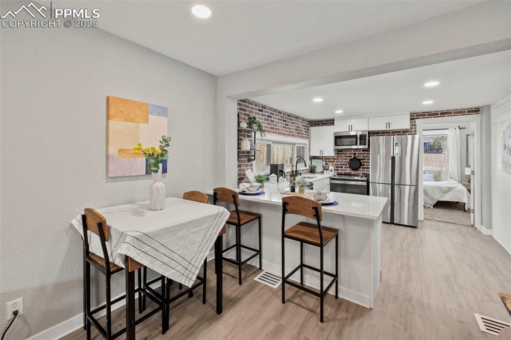 Image 7 of 27: Dining room with light wood-style floors, recessed lighting, a textured wal