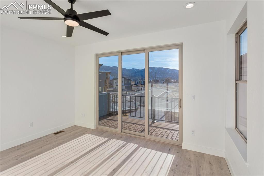 Image 14 of 30: Spare room featuring a mountain view, ceiling fan, and light wood-type floo