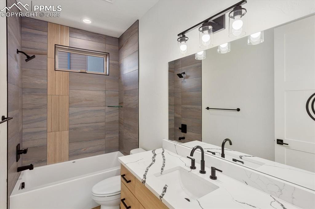 Image 21 of 30: Full bathroom with vanity, toilet, and tiled shower / bath