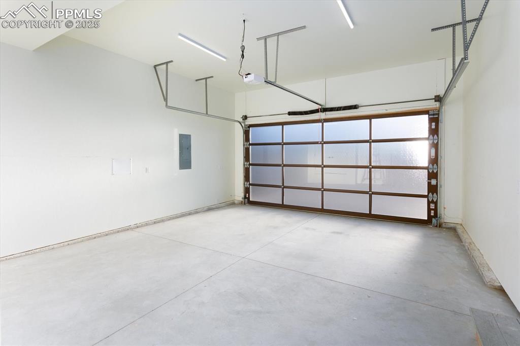 Image 22 of 30: Garage featuring a garage door opener and electric panel