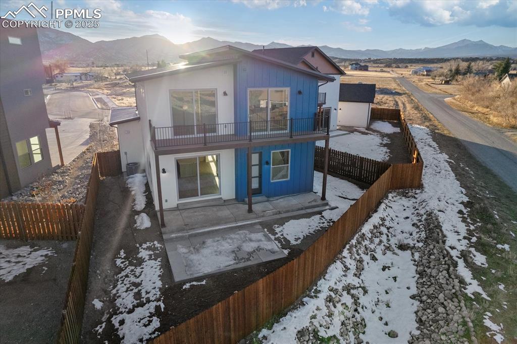 Image 27 of 30: Snow covered rear of property with a mountain view and a balcony