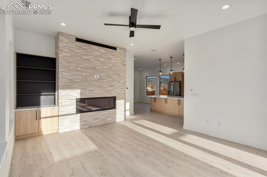 Image 4 of 30: Unfurnished living room featuring a fireplace, light hardwood / wood-style