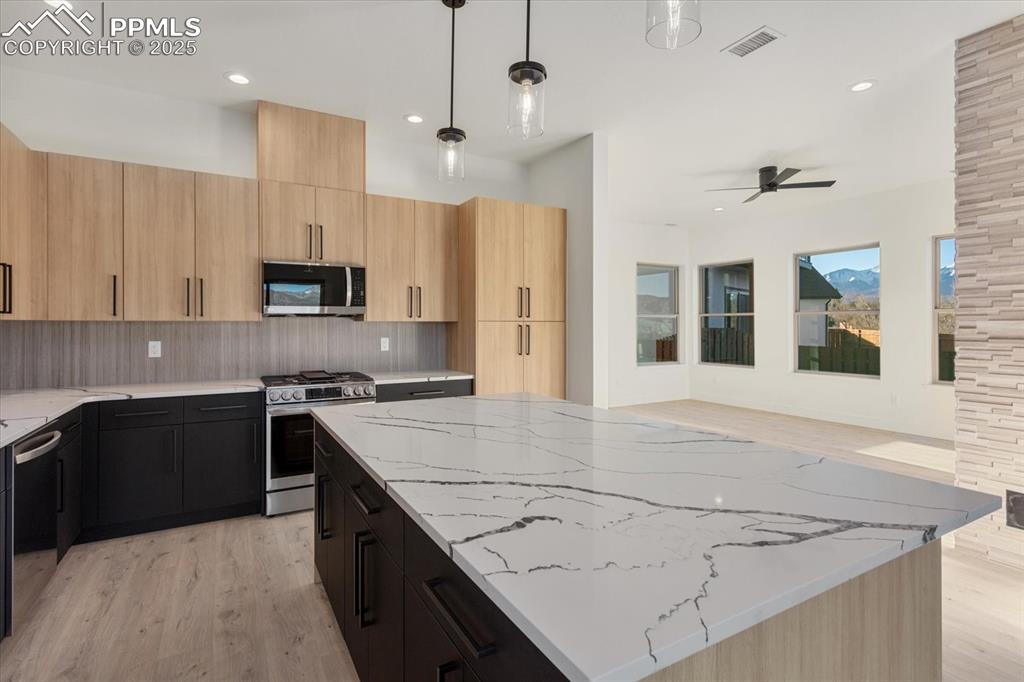 Image 7 of 30: Kitchen with ceiling fan, decorative backsplash, appliances with stainless