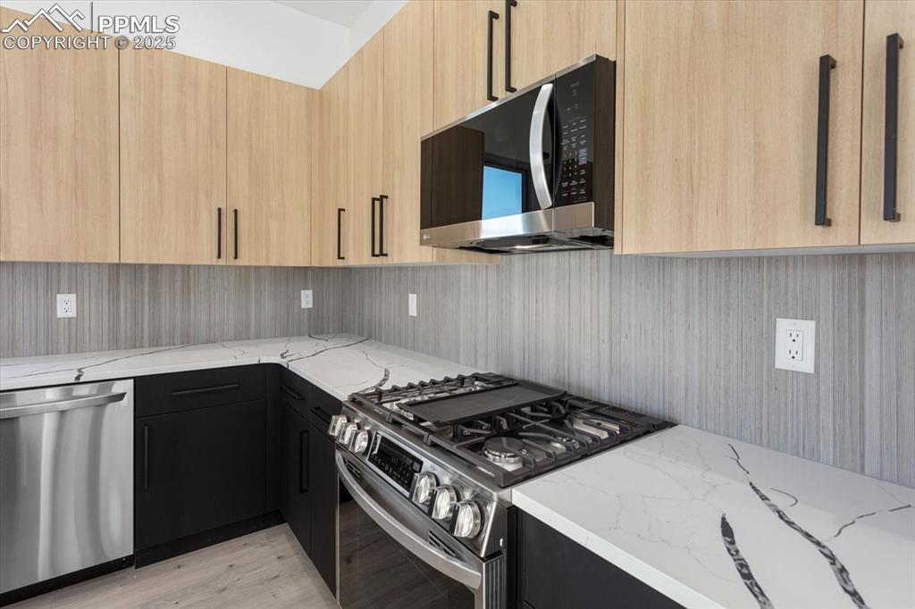 Image 8 of 30: Kitchen with light stone countertops, appliances with stainless steel finis