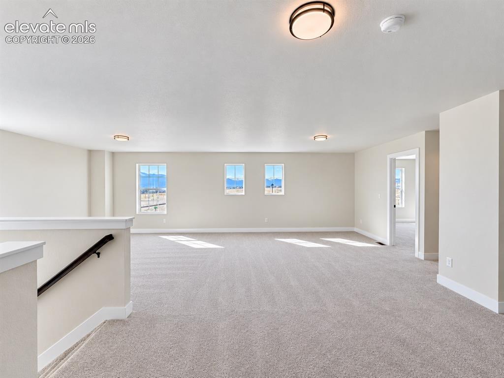 Image 10 of 26: Expansive carpeted room featuring multiple windows, neutral wall tones, and