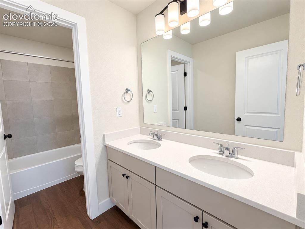 Image 18 of 26: Dual vanity with white countertops and undermount sinks, wood-finish floori