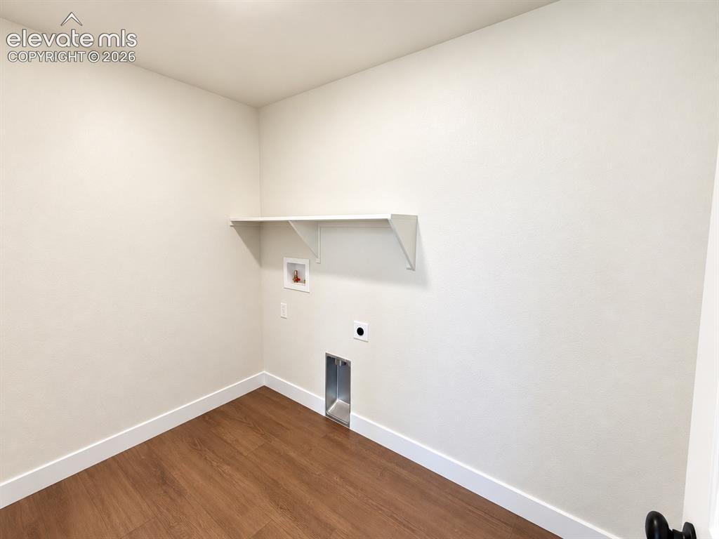 Image 19 of 26: Laundry alcove with wood-finish flooring, a wall-mounted shelf, and applian